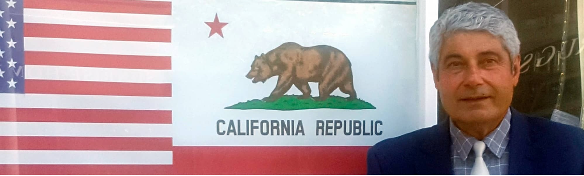 Mahmoud Shirazi in front of the United States and California flags